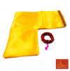 Yellow cloth with green edge trim and a red-black beaded mala with purple tassel