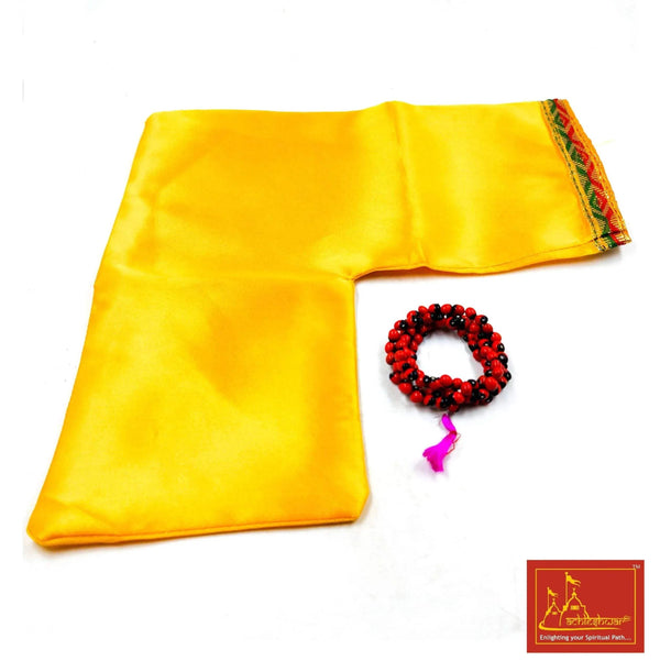 Yellow cloth with green edge trim and a red-black beaded mala with purple tassel