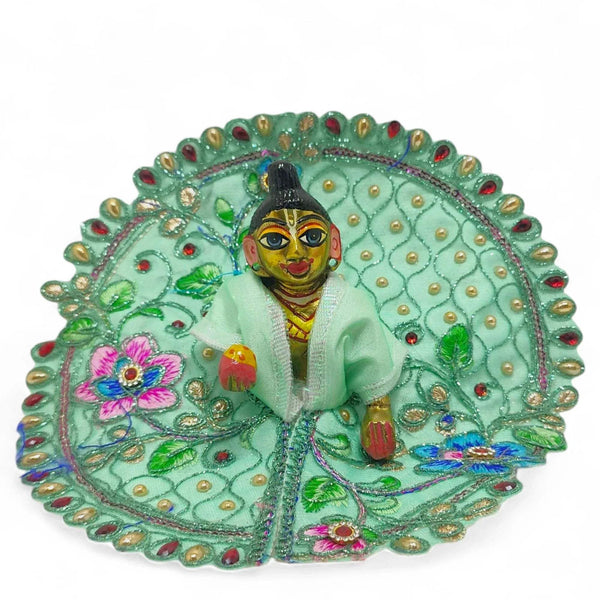 Embroidered Laddu Gopal poshak with jhari work, mint green circular frame with deity figure