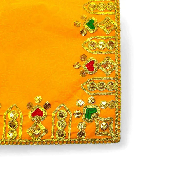 Close-up of yellow velvet pooja asan cloth edge with gold border and multicolor embroidery