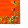 Close-up of orange velvet pooja cloth edge with gold trim and green embroidered motifs
