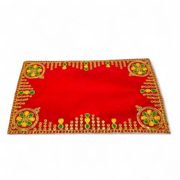 Red pooja aasan cloth with golden border and green floral motifs at each corner