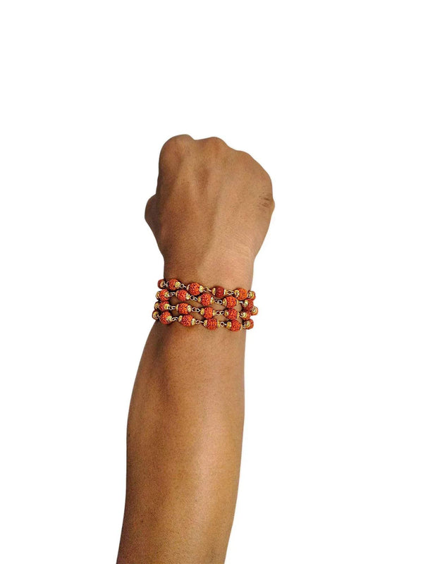 Rudraksha bead bracelet with dark red-brown beads and golden caps on a wrist