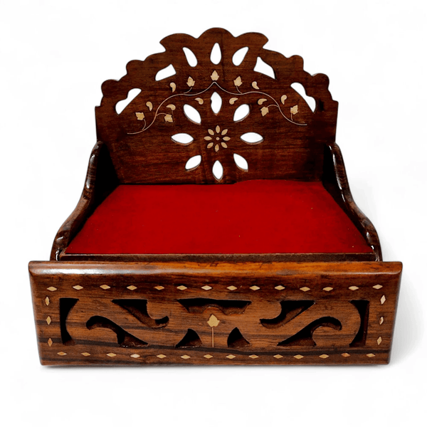 Wooden sofa cum bed with carved backrest and red cushion, front storage panel