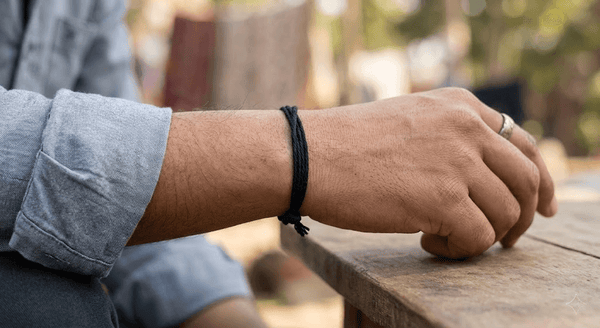 Black thread bracelet tied around wrist