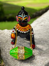 Mini wooden dholak toy with green body, gold chain, and rhinestone center band