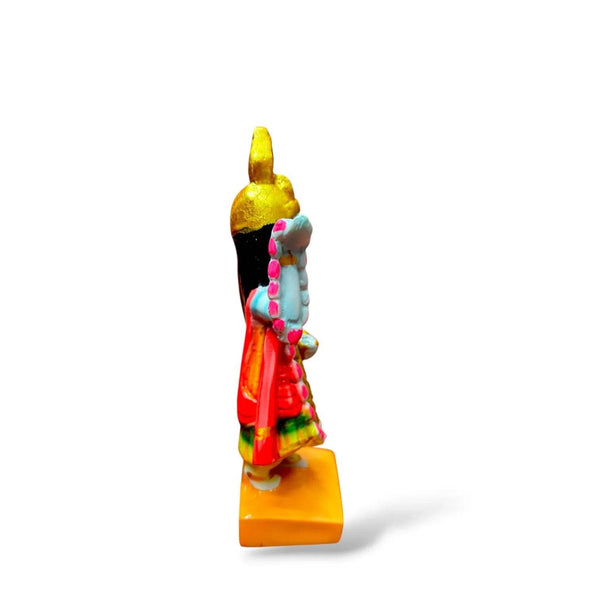 Side-view blue-skinned goddess statue with gold crown, red skirt, raised arm, yellow base