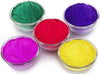 Assorted gulal powder in five small bowls: green, purple, red, pink, and yellow