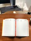 Open diary with ruled date pages and red binding, showing '23' marker