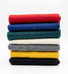 Stack of colored wool meditation mats in red, blue, green, cream, yellow, and gray