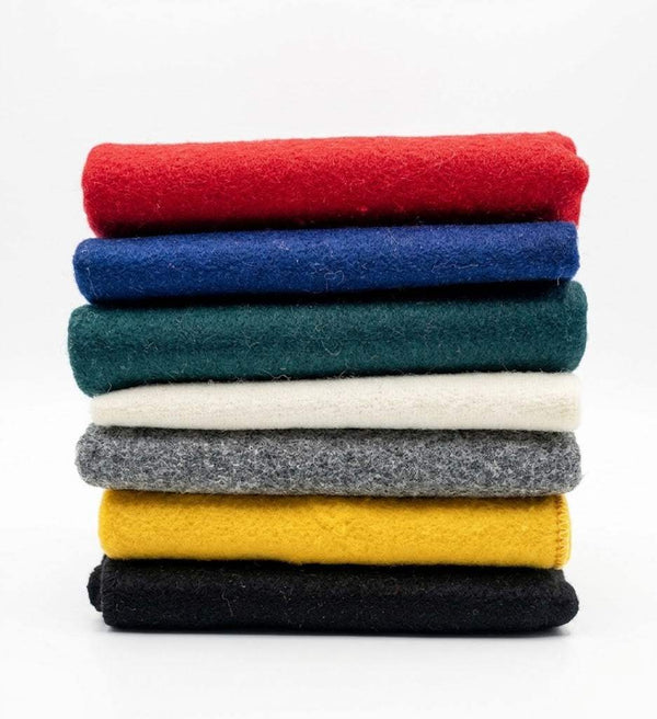 Stack of colored wool meditation mats in red, blue, green, cream, yellow, and gray