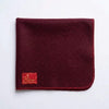Maroon woolen Aasan mat with stitched border and logo patch at lower left