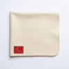 Off-white woolen pooja mat with red logo patch on lower left corner