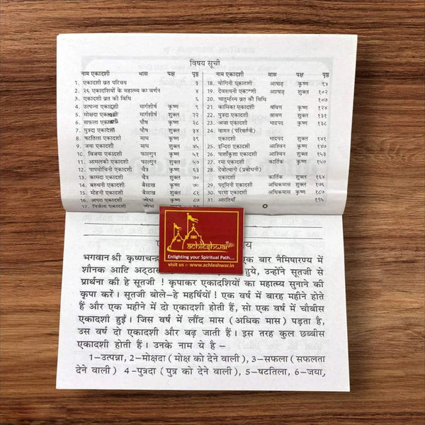Open religious Hindi vrat katha book with printed text pages and small colored seal