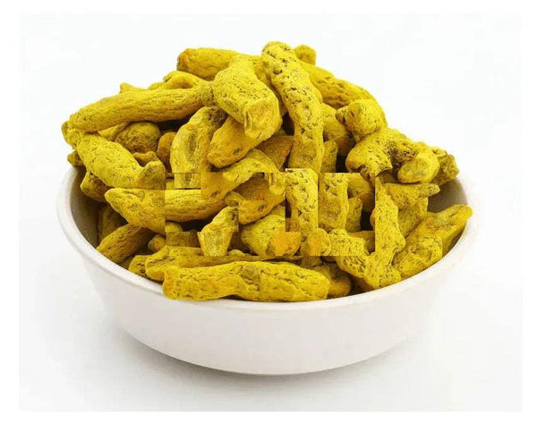 Yellow turmeric rhizome pieces in a white bowl