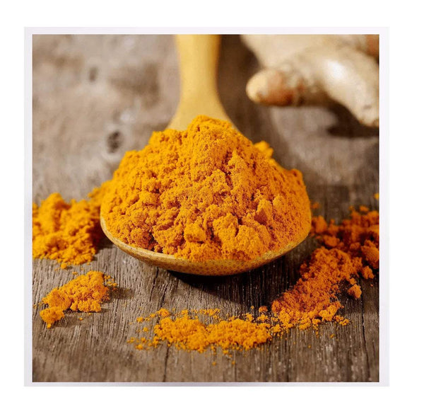 Turmeric powder mounded in a wooden spoon on rustic wooden boards