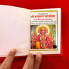 Open red pocket book showing printed Hindi text and colorful Hanuman illustration