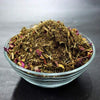 Hawan samagri dried herb mix in a glass bowl with small pink flower bits
