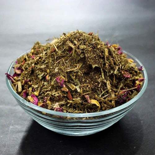 Hawan samagri dried herb mix in a glass bowl with small pink flower bits