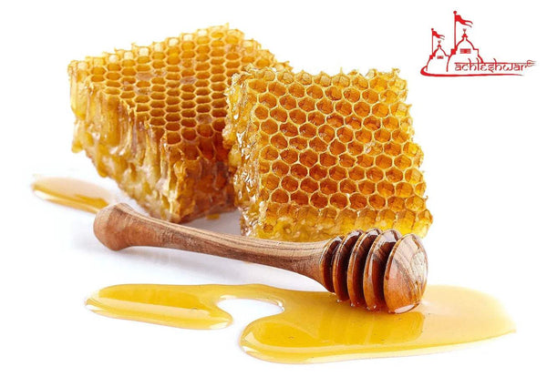 Honeycomb pieces with wooden honey dipper and honey drippings