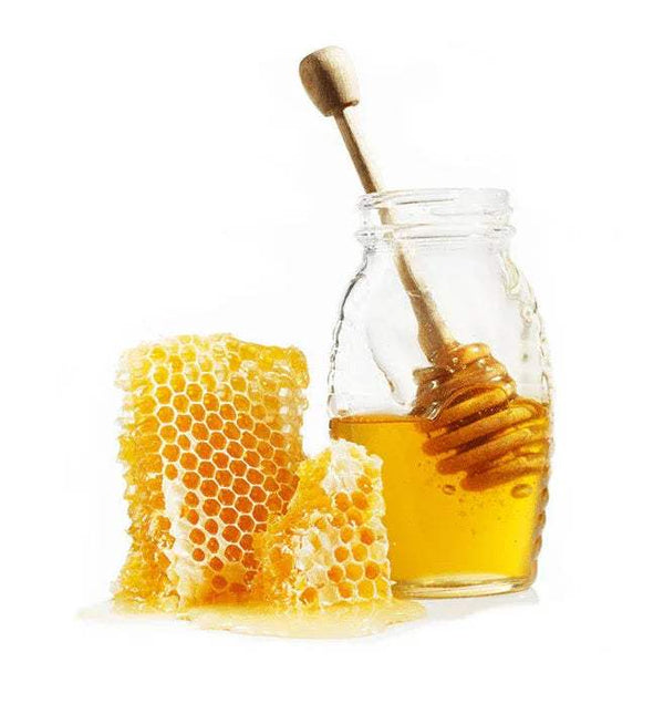 Honey in glass jar with wooden honey dipper and honeycomb
