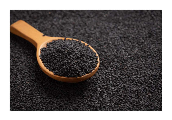 Black sesame seeds in wooden spoon on dark sesame seeds