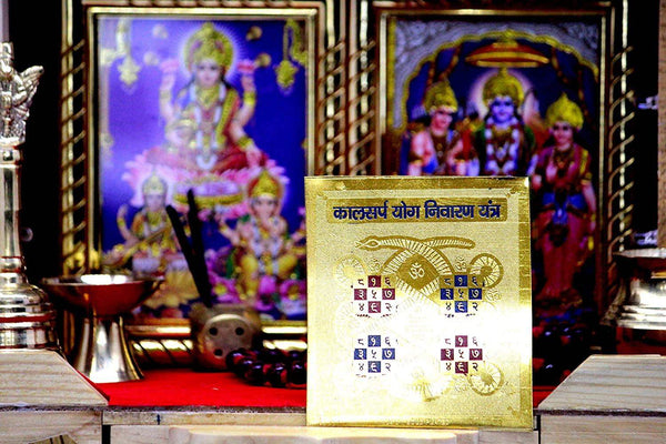 Gold-colored yantra card placed on a temple surface in front of deity displays