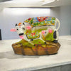 Cow and calf figurine with white body, black horns, green patterned saddle, brown base.