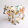 Handcrafted cow idol with calf, white and gold accents, painted deity scenes and bell