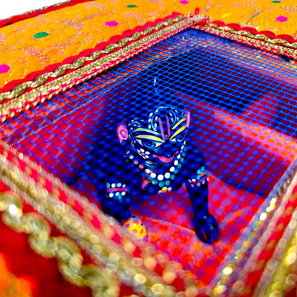 Decorative velvet storage box interior with blue Krishna deity and mesh base