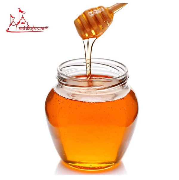Amber honey in glass jar with wooden honey dipper drizzling
