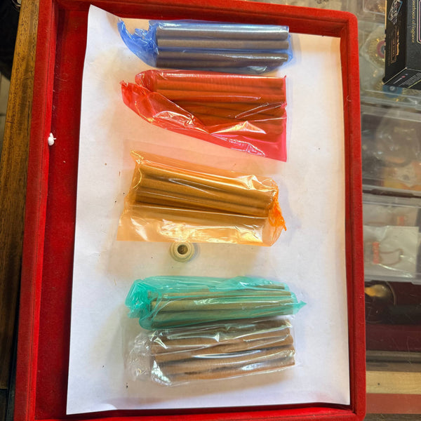 Dhoop incense sticks set in red tray, wrapped bundles of blue, orange, yellow, and green sticks