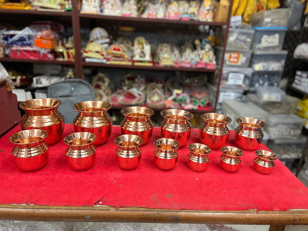 Premium pure copper pooja lota set, assorted small copper kalash vessels lined on red cloth.