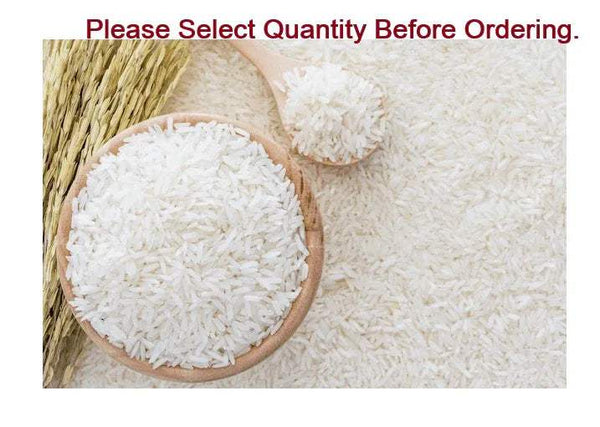 Uncooked white rice grains with a wooden spoon and wooden bowl