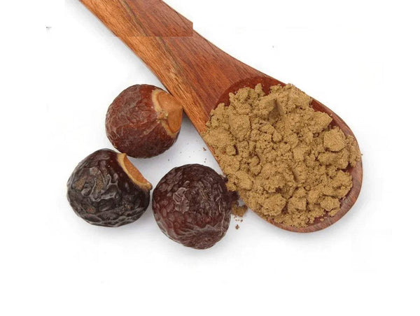 Ritha powder in wooden scoop with brown dried root pieces