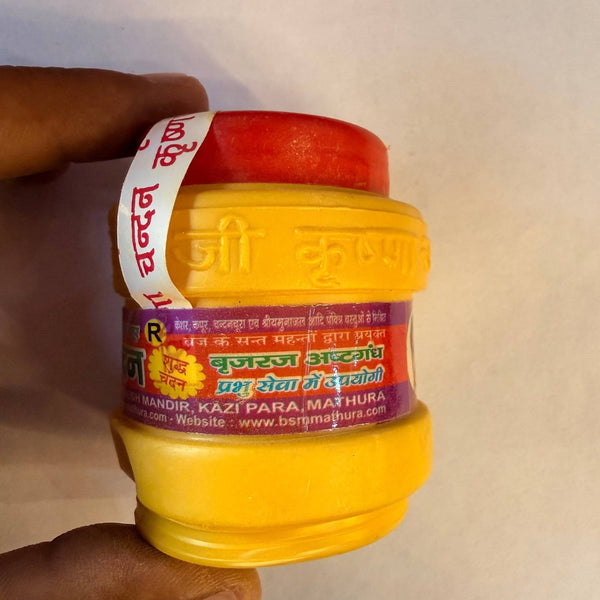 Chandan powder jar with red cap and yellow label, for puja rituals