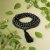 Black tulsi bead mala with tassel, round beads laid in a loop on leaves