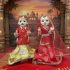 Rajasthani idol pair in red outfits with gold skirts, one veiled and seated