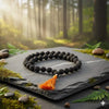 Black rudraksha bead mala with orange tassel on a flat stone slab