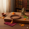 Rudraksha bead mala on wooden board, natural brown beads with orange tassel
