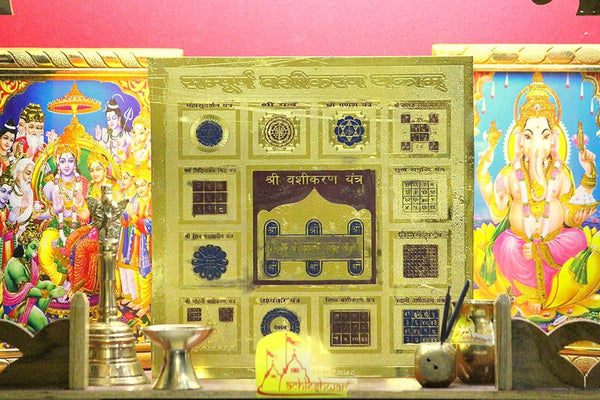 Golden plated yantra plate in an altar setting with blue and gold printed designs
