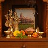 Puja altar display with gold figurines, candles, flowers, and ritual offerings