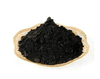 Black incense powder mounded in a shallow wooden bowl
