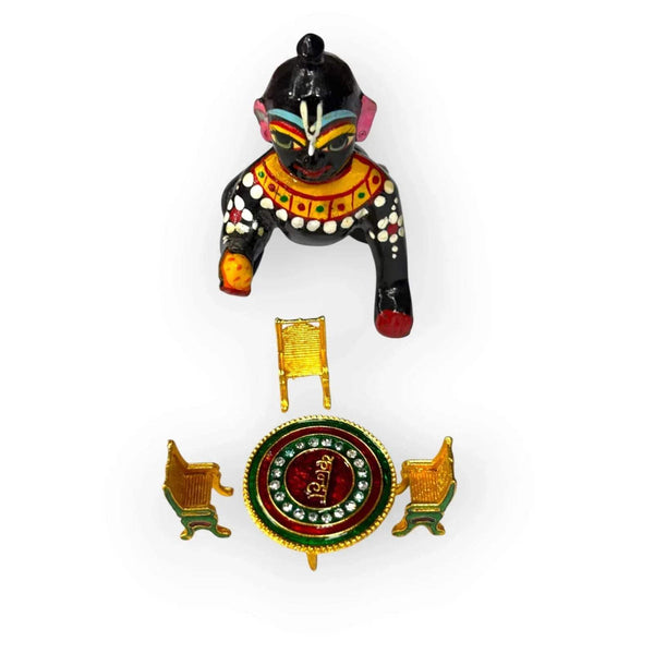 Krishna idol with toy dining table and four small chairs, round red tabletop