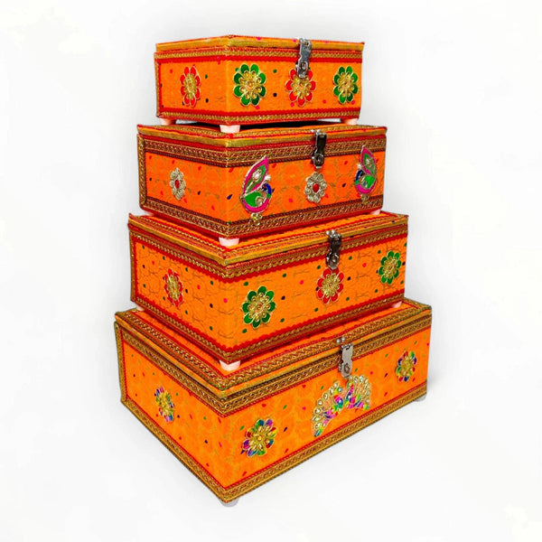 Stacked decorative velvet storage boxes with orange panels and floral embellishments