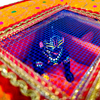 Decorative velvet storage box interior with blue Krishna deity and mesh base