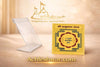 Yantra card displayed on a clear acrylic stand, yellow design with central emblem